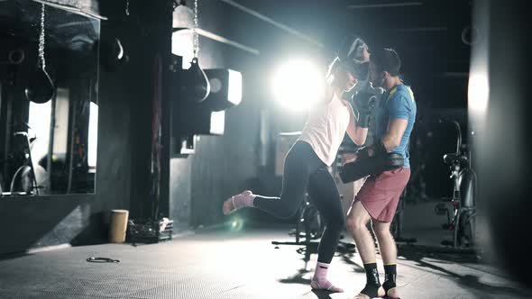 A Athlete Woman Fighter is Training Punches Focus Mitts in the Dark Gym alt