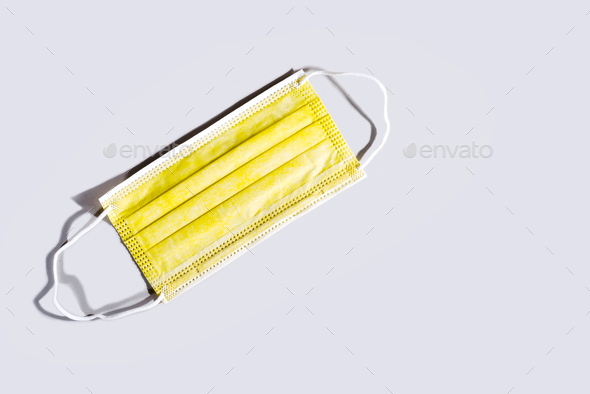 Yellow surgical face protection mask isolated on gray background. Trendy colors 2021.