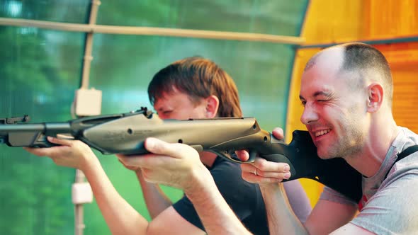 Close-up: Young Guys Shoot at Shooting Range From Pneumatic Guns, Recharge Cartridges alt