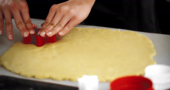 Women's Hands Squeeze Out a Star Mold on a Rolledout Sand Dough