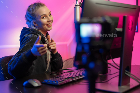 Funny and smiling e-sport gamer girl vlogging and plays online video game  on PC Stock Photo by kjekol