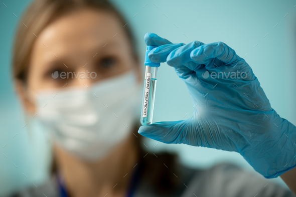 Gloved hand of researcher holding small flask with sample of new vaccine