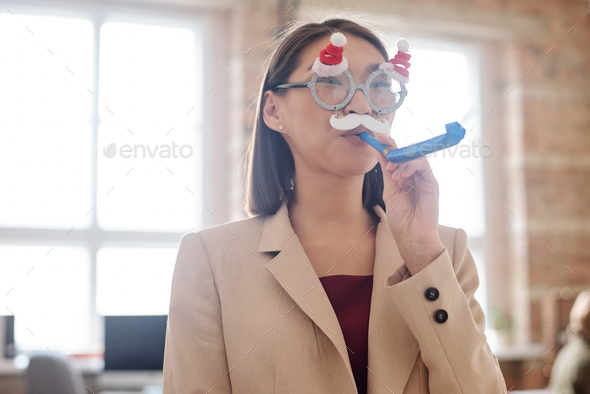 Young elegant businesswoman in xmas eyeglasses with moustache blowing whistle