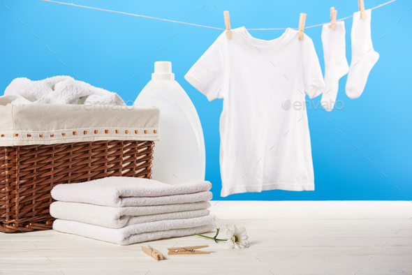 laundry basket, plastic container with laundry liquid, pile of clean soft towels and white clothes