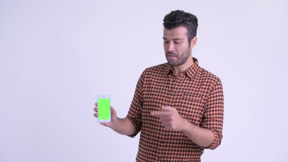 Happy Bearded Persian Hipster Man Showing Phone and Giving Thumbs Up alt