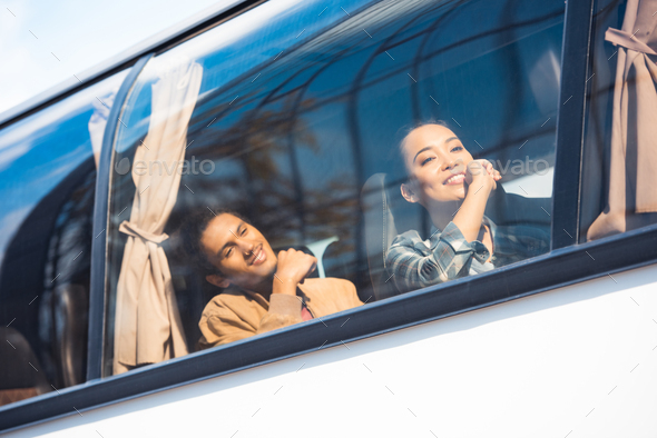 happy asian and mixed race tourists during trip on travel bus