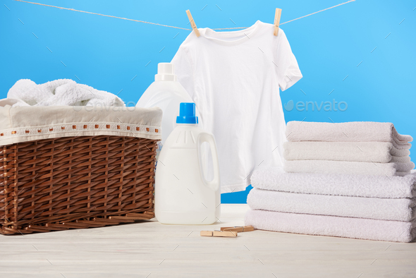 plastic containers with laundry liquids, laundry basket, pile of towels and clean white clothes