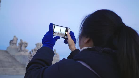 Back view of Asian woman standing and taking a photo in public Frogner park, Norway alt
