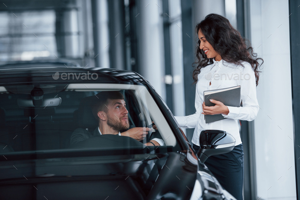It's yours now. Male customer and modern businesswoman in the automobile saloon