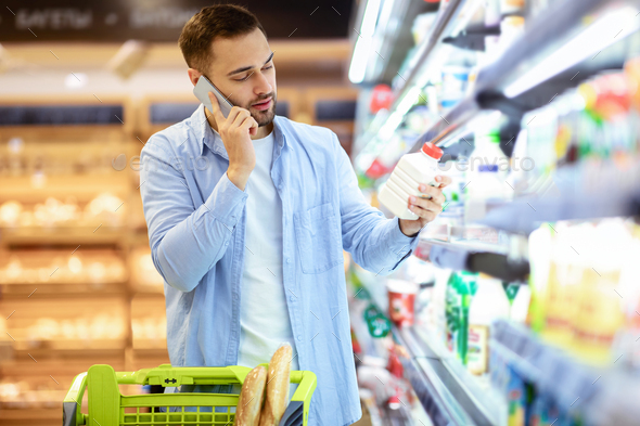 Portrait of man shopping groceries, buying milk, talking on phone