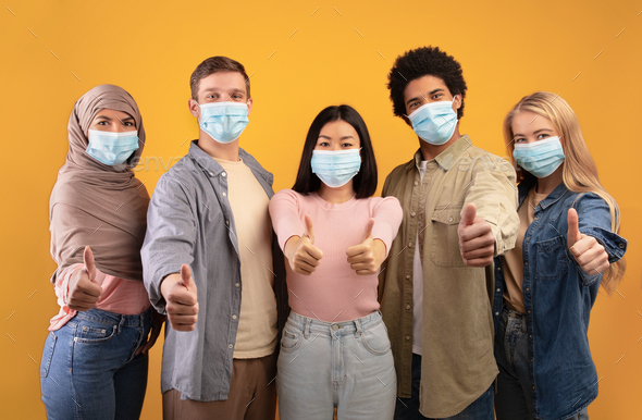 International multi-ethnic student exchange. Young multiracial people in protective masks showing