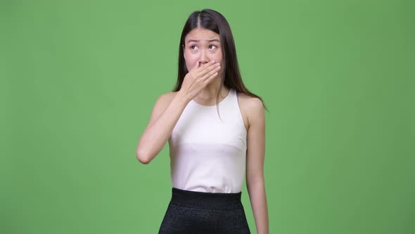 Young Beautiful Asian Businesswoman Covering Mouth While Looking Guilty