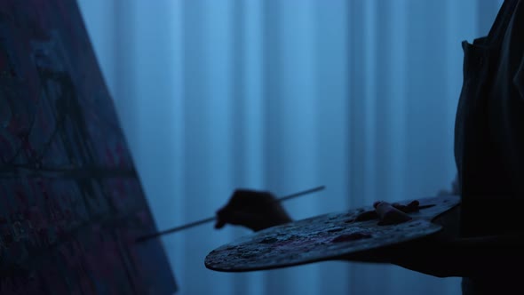 Silhouette of Woman's Hand Draws a Picture with Oil Paints on Canvas with a Brush alt