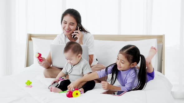 Asian Mother with baby daughter girl and baby using laptop home lifestyle alt