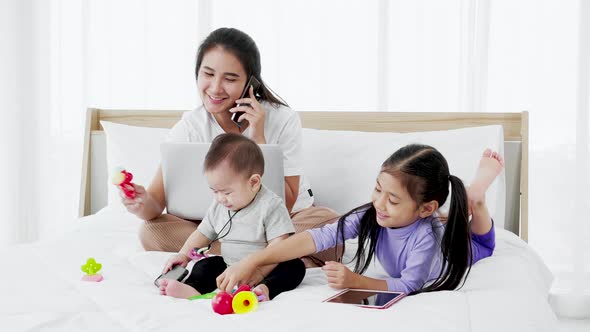 Asian Mother with baby daughter girl and baby using laptop home lifestyle