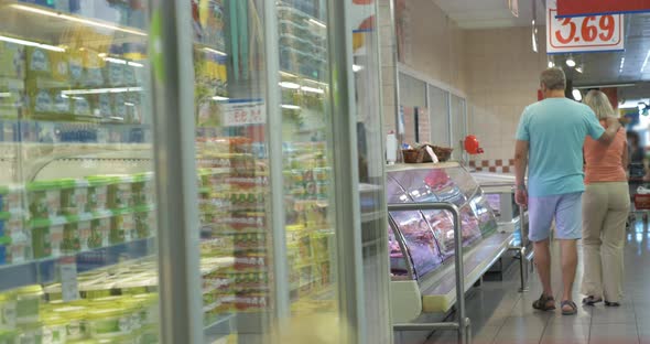 Couple Walking along the Fridges in Supermarket alt