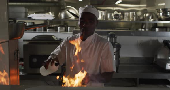 African american male chef frying in pan in restaurant kitchen alt
