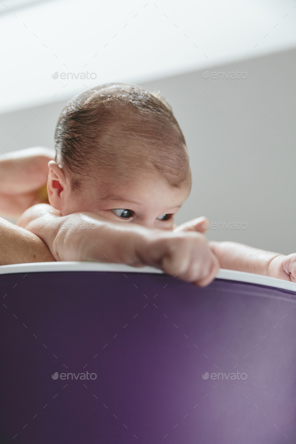 Newborn in the bathtub held by her mother