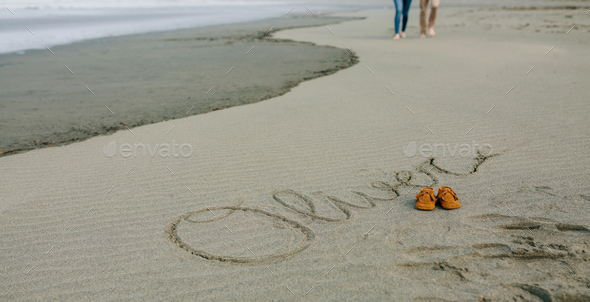 Baby name written in sand with shoes - Stock Photo - Images