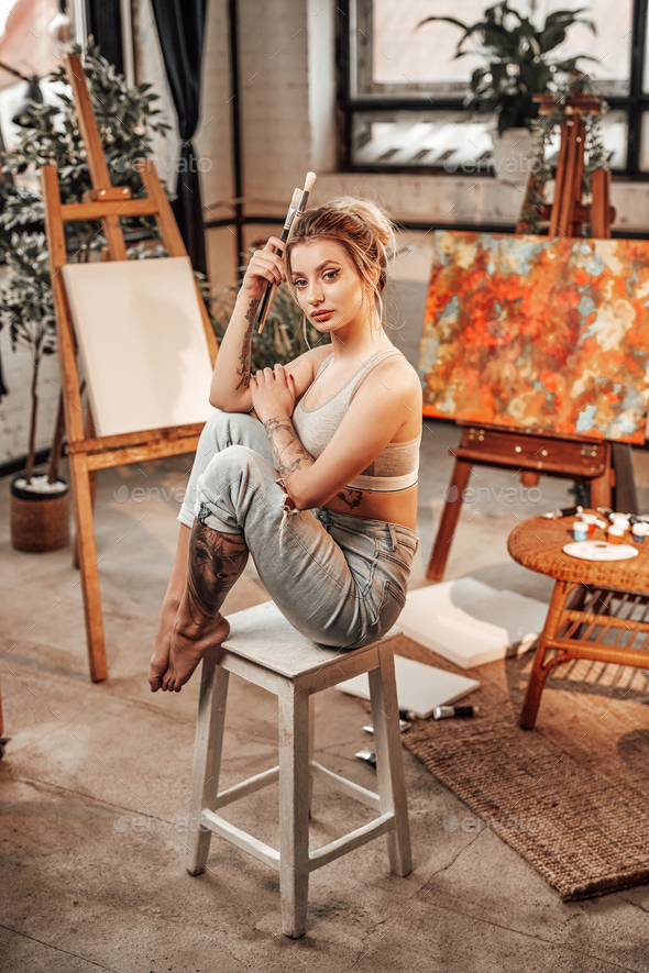 Beautiful woman painter sitting on chair with paintbrushes