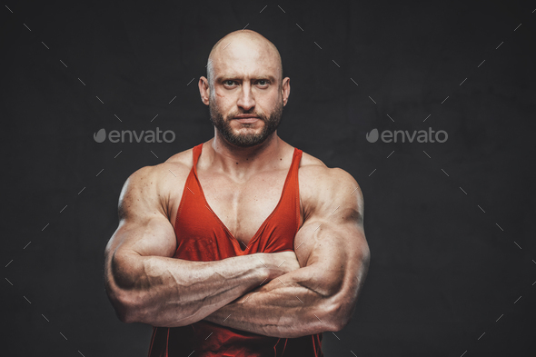 kontrast video Kommerciel Bald strong man in red shirt poses in dark background with crossed arms  Stock Photo by fxquadro