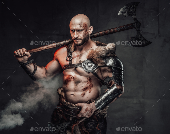 Violent topless viking holding huge axe on his shoulder in smokey ...