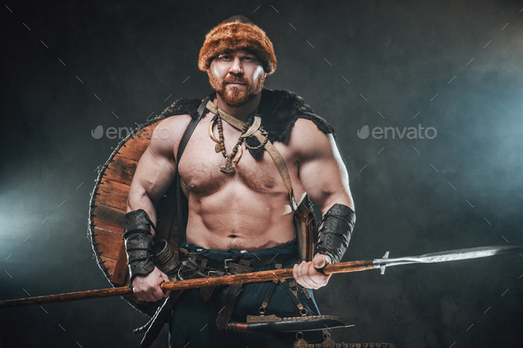 Shirtless viking armed with spear poses in smokey background Stock ...