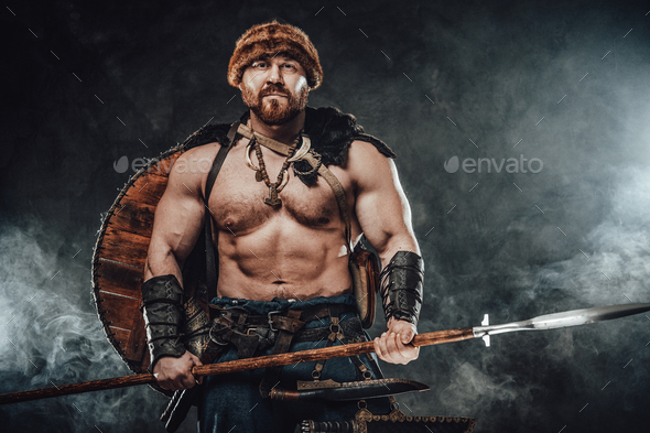 Shirtless viking armed with spear poses in smokey background Stock ...