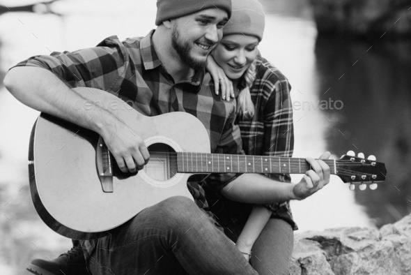 a guy in a bright hat plays the guitar with a girl against a background of granite rocks