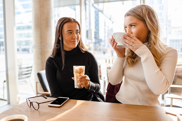 Smiling Women Talking and Drinking Coffee At Modern Cafe in City Stock