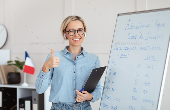 Friendly female teacher recommending foreign languages school, showing thumb up gesture, giving