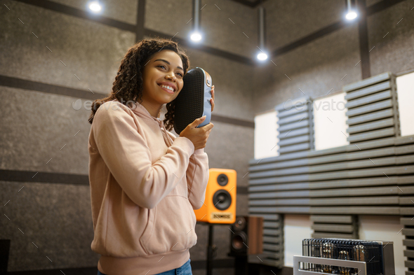 Smiling woman holds sound speaker in store