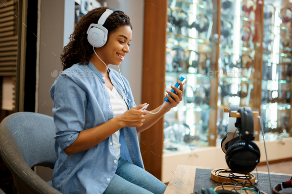 Young woman listening to music, headphones store