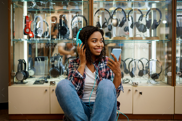 Happy buyer choosing headphones in audio store