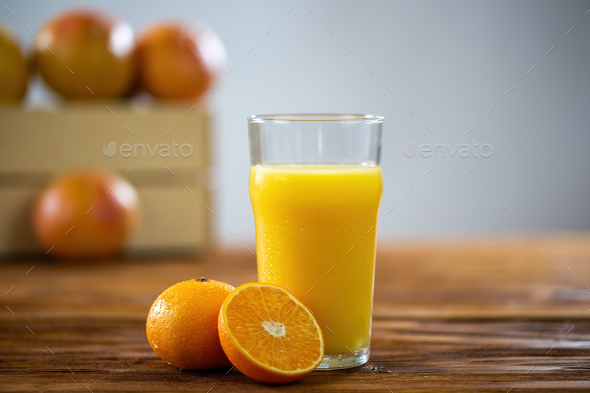 Glass of fresh orange juice on wooden table with grapefruits in background  Stock Photo by WildMediaSK