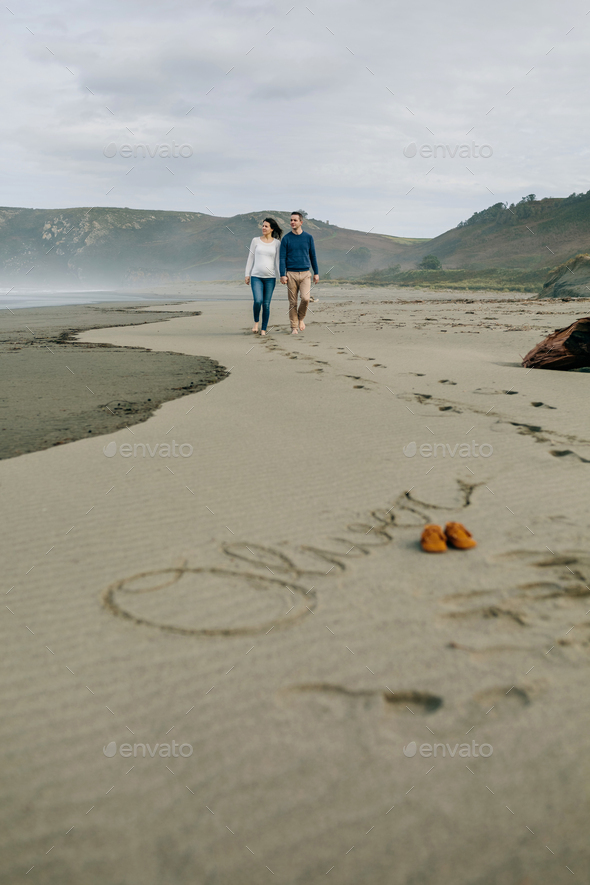 Parents walking with baby name Oliver written in the sand - Stock Photo - Images