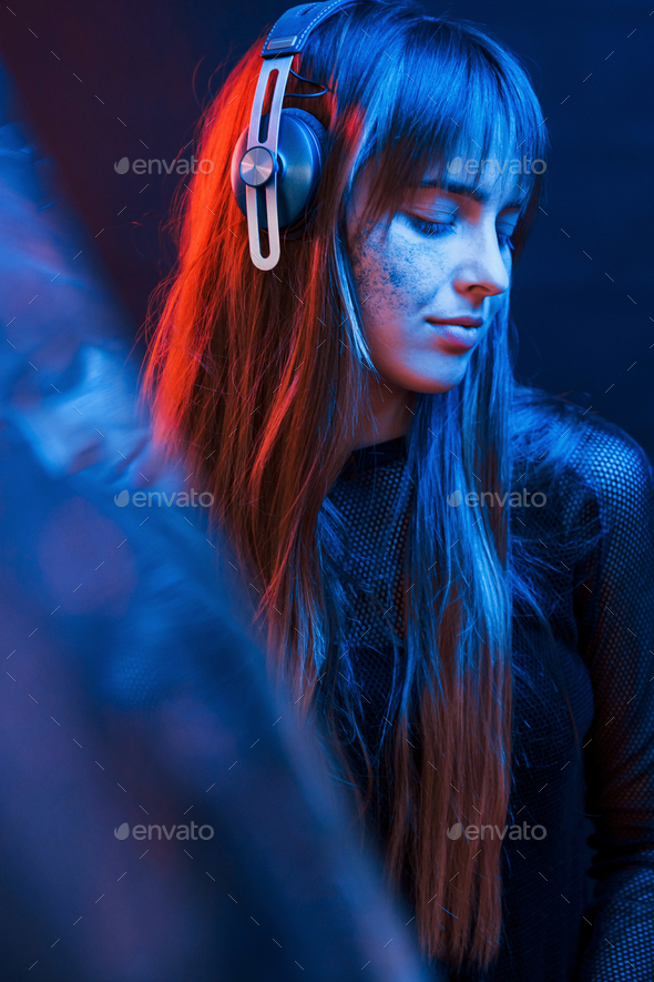 Attention to details. Studio shot in dark studio with neon light. Portrait of young girl