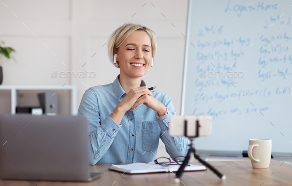 E learning and online tutoring. Positive female teacher conducting online math class on smartphone