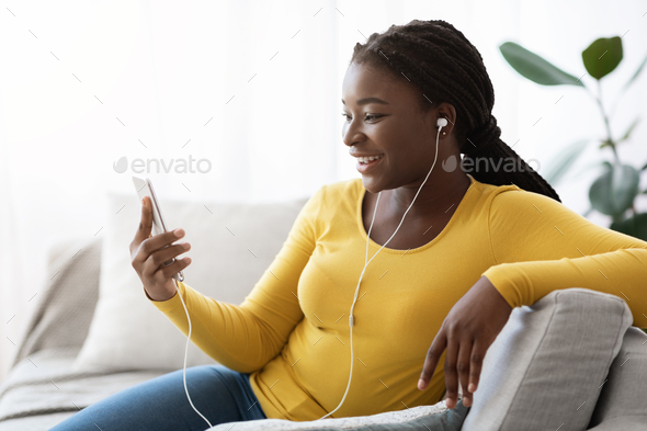 Black Female Listening Music Or Making Video Call On Smartphone At Home