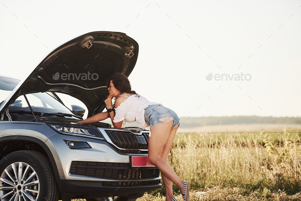 Made it by yourself. Hot woman open hood of her broken car and fixes it at countryside