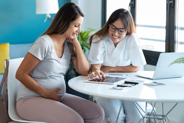 Gynecologist doctor showing to pregnant ultrasound scan baby with digital tablet in consultation. - Stock Photo - Images