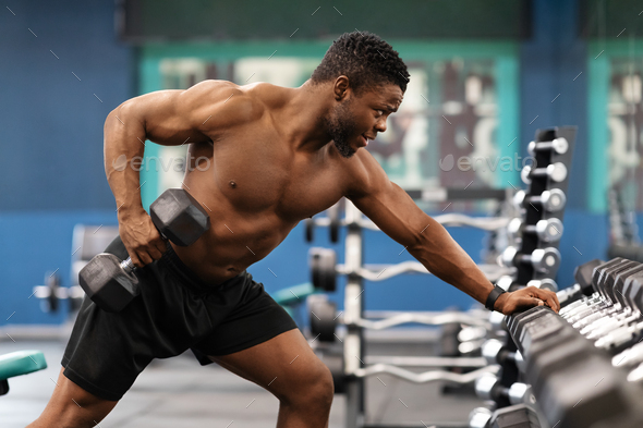 Concentrated black athlete training arms with dumbbells at gym Stock Photo  by ©Milkos 446182836