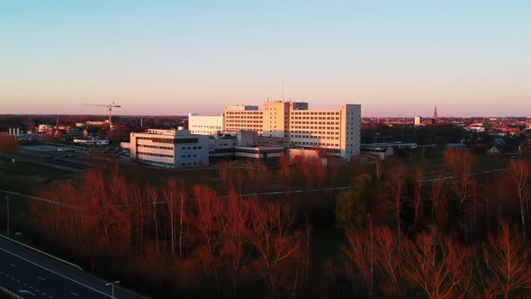 A beautiful drone shot of a hospital surrounded by red trees filmed at sunset. alt