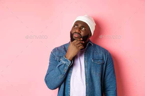 Image of puzzled and concerned black man, staring at upper left corner and thinking, making decision