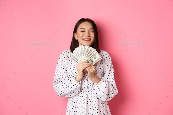 Shopping concept. Happy and satisfied asian woman winning prize money, showing dollars and rejoicing