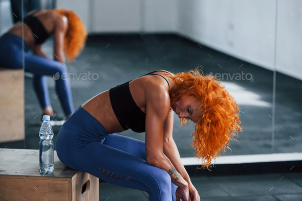 Strong abs. Young woman with slim body type and in yoga clothes is at home  Stock Photo by mstandret