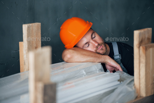 Taking a break. Industrial worker indoors in factory. Young technician with orange hard hat