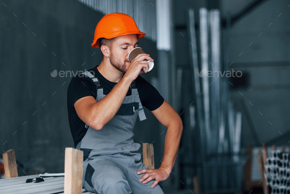 Industrial worker indoors in factory. Young technician with orange hard hat