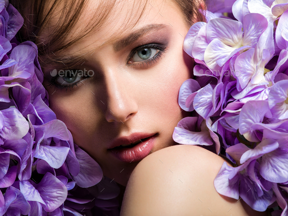 Pretty woman with bright makeup. Beautiful white girl with purple flowers. - Stock Photo - Images