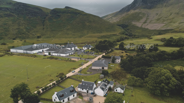 Arran whiskey distillery aerial. Road in green mountains valley. Scottish village with houses, camp
